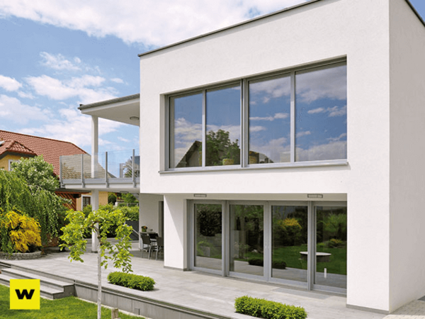 Modernes Einfamilienhaus mit großer Terrasse, bodentiefen Fenstern und Garten im Grünen.